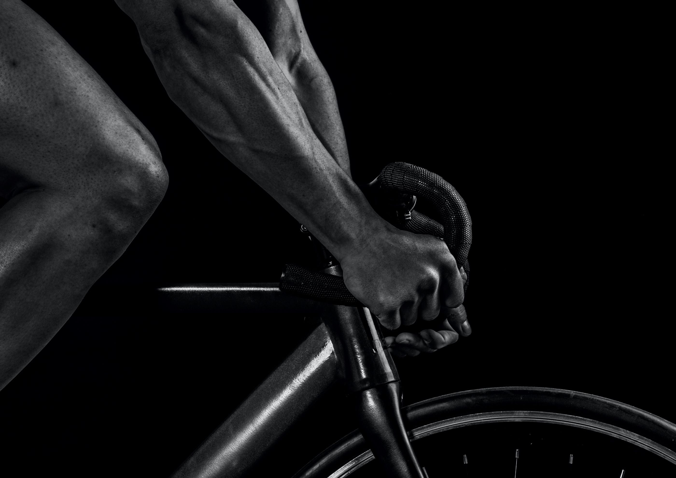 Close up of man riding a bicycle in black and white showcasing home gym equipment from The Fitness Connection