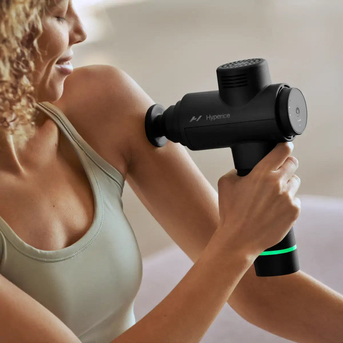 Woman using a therapy percussion gun from Hyperice 2 for muscle recovery and performance.